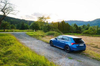 Off road traveling in blue Skoda Scala car at countryside road at sunset, August 2022, Dolni Morava, Czech Republic