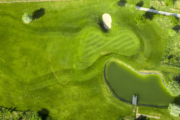 Golf course with sand bunker and green grass, aerial view.
