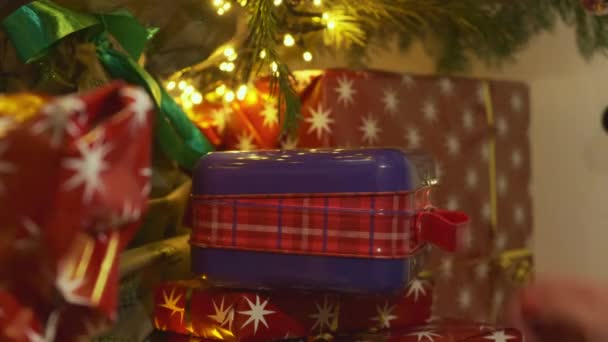 人はおもちゃやガーランドで装飾されたクリスマスツリーの下に存在する照明付きの箱を開きます 箱の中に新年のプレゼントを閉じ — ストック動画