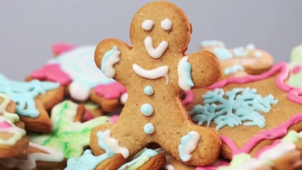 ジンジャーブレッドの男は 白い霜降りアイスクリームのトッピングで飾られた ジンジャーブレッドは クリスマスのお祝いのための焼きクッキーのヒープ上にありますクローズアップ — ストック動画