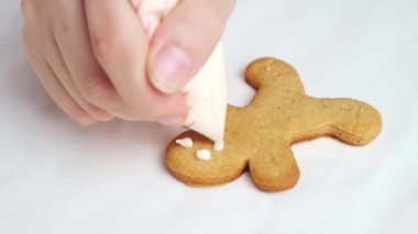 Şef zencefilli çörek çizen adamı beyaz krema sosuyla süslüyor Noel 'i kutlamak için kurabiye yapıyor. Şekerlemeci ilginç desen çizer