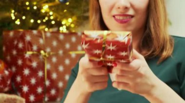 Kızıl saçlı kadın, Noel ağacının yanındaki arkadaşına altın kurdeleyle süslenmiş hediyesini veriyor. Yeşil tişörtlü kızıl kadın Noel 'i kutlamak için heyecanlı