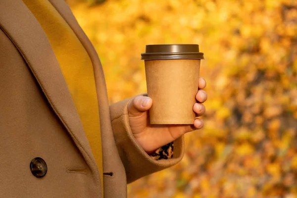 把拿着一杯咖啡的女人关在秋天的森林里 一个穿着棕色外套的女人走在秋天的公园里 — 图库照片