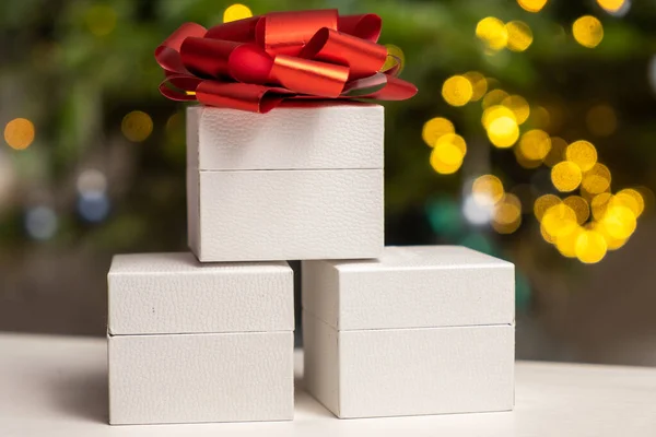 Pyramid of white boxes with a red bow under the Christmas tree. Gifts for Christmas and Happy New Year.