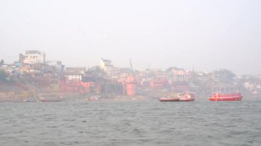 Varanasi, Utter pradesh, Hindistan, 3 Ocak 2022, ghatlardan kutsal Varanasi şehri manzarası. Nehrin kıyısına demirlemiş tekneler.