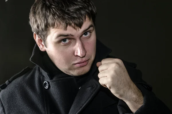 bir yumruk ile siyah montlu genç bir adam