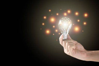 Siyah arka planda aydınlatmalı tungsten ampulü tutan tanınmamış bir adam var. Yaratıcılık ve fikir kavramı. Ağ çizgisi olan ampul.