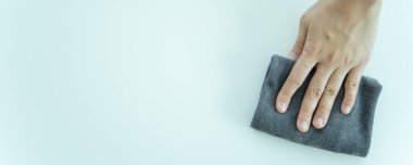Masanın yüzeyine mikrofiber silen tanınmayan Asyalı bir temizlikçi. Kopyalama alanı ile yakın plan. Hizmetçi kirli bir yüzeyi temizleyip sterilize ediyor..