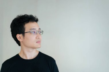 Yakışıklı, arka planda siyah tişörtlü gözlüklü, mutlu Asyalı genç adam. Asyalı genç adamın portresi.