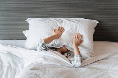 Asyalı genç bir kadın yataktan kalkıyor ve kollarını açıyor. 20 'lerin Asyalı tembel kadını uyanıyor..