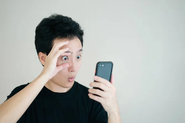 Funny Excited Asian Young Man Touching His Eyes Looking Smartphone — Stock Photo, Image
