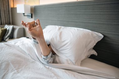 Asyalı genç bir kadın yataktan kalkıyor ve kollarını açıyor. 20 'lerin Asyalı tembel kadını uyanıyor..