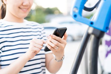 Şarj istasyonu, Bev veya elektrikli araç şarj istasyonu ile akıllı telefon bağlantısı kurmak için her türlü şarj uygulamasını kullanan mutlu Asyalı genç kadın. EV istasyonunda yakıt ikmali yapan kadın..