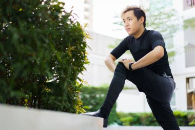 Parkta egzersiz yapmadan, esneme ve egzersiz yapmadan önce alt ve üst vücut esneme hareketleri yapan mutlu Asyalı genç sporcu. Spor adamı kardiyo ve ağırlık çalışması yapıyor..