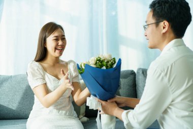 Sevgililer Günü 'nde ya da yıldönümünde mutlu Asyalı genç bir çift sevgililer gününde karısına bir buket çiçek verir ve sürpriz yapar. Karı koca Sevgililer Günü 'nde kutlama yapıyorlar..