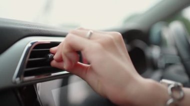 Yağmurda araba kullanırken arabanın ön paneline hava ızgarası yerleştiren bir kadın. Havalı ve sıcak klimalı modern arabada iklim kontrol sistemi. Sıcaklık denetimi.