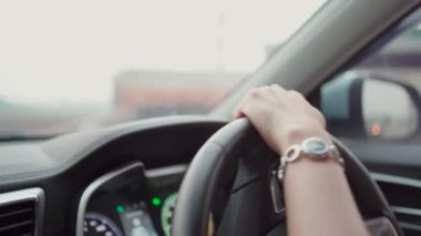 Yolda giderken direksiyonda sol elini kullanan tanınmayan kadın sürücü, yolda güzel bir gün ışığında modern elektrikli araba kullanan kadın. Güvenli sürüş kavramı.