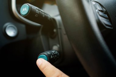 Tanımlanamayan adam sürücü, adaptif seyir kontrolünü etkinleştiriyor ya da direksiyondaki kontrol çubuğunda direksiyon asistanını çalıştırıyor. Modern otomobilde Sürücü Yardım Sistemi.