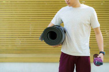 Aktif Asyalı sporcu egzersiz ya da yoga minderi açıyor. Asyalı sporcunun sağlıklı ve formda vücudu vücut ağırlığı ve kardiyo egzersizi için yoga minderi hazırlıyor..