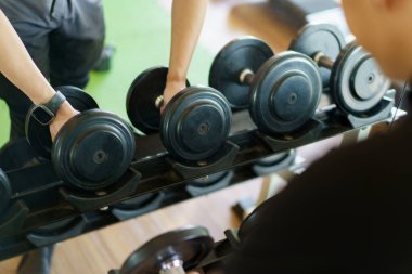 Aktif Asyalı sporcu spor salonunda ağırlık egzersizi yapıyor. Bir dambılı kaldırarak ya da halterden ağır bir dambıl tutarak spor yapıyor..