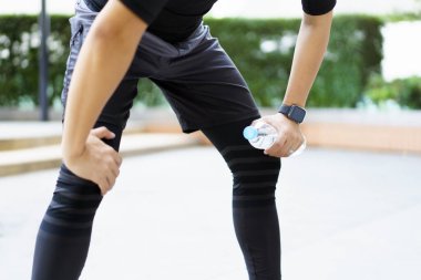 Aktif Asyalı sporcu açık hava koşusu ve antrenmandan sonra şişede su içiyor. Asyalı adam egzersize ara verdiğinde su içer. Sağlıklı bir adam kardiyo çalışması için çok çalışıyor..