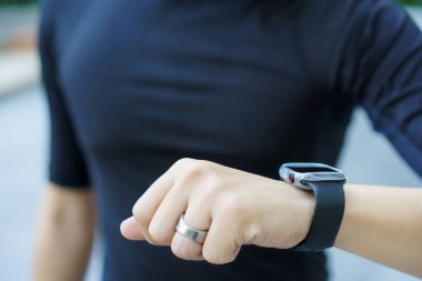 Aktif Asyalı genç sporcu, spor yapmak için akıllı spor bandı ya da akıllı fitness bandı kullanıyor. Açık hava egzersizlerini ve aktivitelerini takip ediyor..