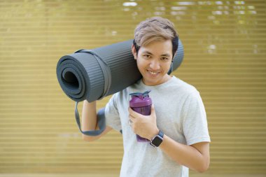 Aktif Asyalı sporcu egzersiz ya da yoga minderi açıyor. Asyalı sporcunun sağlıklı ve formda vücudu vücut ağırlığı ve kardiyo egzersizi için yoga minderi hazırlıyor..