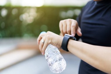 Aktif Asyalı genç sporcu, spor yapmak için akıllı spor bandı ya da akıllı fitness bandı kullanıyor. Açık hava egzersizlerini ve aktivitelerini takip ediyor..