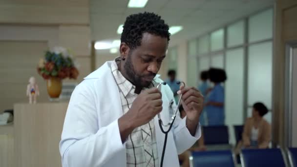 4Kポートレート映像 アフリカ系アメリカ人医師が病院で腕を交差させ 医師の肖像画がぼやけた病院病棟の背景を持つ — ストック動画