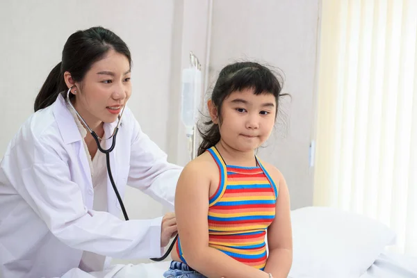 Professional specialist doctor examining about breathing in Asian little girl in kids hospital. Doctor kindly checking and listening heartbeat in little girl.