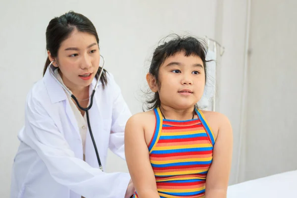 Professional specialist doctor examining about breathing in Asian little girl in kids hospital. Doctor kindly checking and listening heartbeat in little girl.