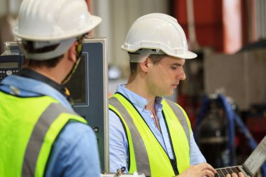 Kafkasyalı endüstriyel mühendis bir fabrikada çalışıyor ve birlikte tartışıyorlar. Metal işçiliği ölçen ve bir rapor belgesini inceleyen kıdemli mühendis veya müteahhit.