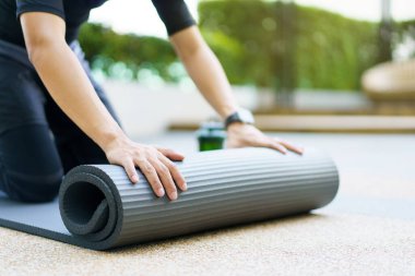 Aktif Asyalı sporcu, vücut ağırlığı ve kardiyo egzersizi için bir yoga minderi hazırlayan Asyalı sporcunun sağlıklı ve formda vücudunu yere seriyor..