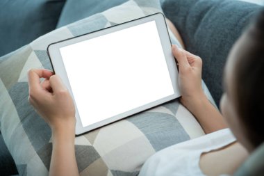 Maket tablet ekranındaki kırpma yolu ile izole edilmiş, oturma odasında kanepede otururken tablet kullanan ya da internette gezinen bir kadın - sosyal medya. Sosyal ağda sörf yapan kadın.