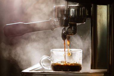 Barista küçük bir kahve dükkanında yüksek basınçlı espresso makinesi kullanarak kahve yapıyor. Kahve dükkanındaki kahve makineleri..