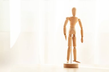 Pencerenin yanındaki tahta masanın üzerinde tahta anatomi figürü var. Tasarımcı için ahşap insan vücudu modeli.