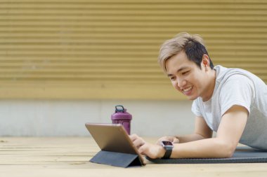 Aktif sporcu bir kalas egzersizi yapıyor ve çevrimiçi bir arkadaşı ve spor antrenörü ile video görüşmesi yapıyor. Çevrimiçi eğitmenle vücut geliştirme çalışması yapan sağlıklı bir sporcu..