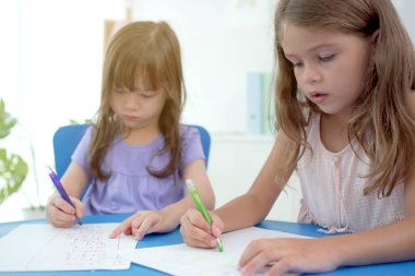 Mutlu Kafkas ve Asyalı genç ilkokul çağları öğretmenleriyle birlikte öğrenmenin ve oynamanın keyfini çıkarıyorlar. Erkekler ve kızlar sınıfta sanat ve matematik okuyorlar..