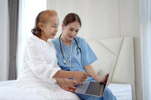 Female doctor comes to talk to elder patient in the hospital about the medical diagnosis. Doctor explaining a medical diagnostic result on laptop computer to old woman patient.