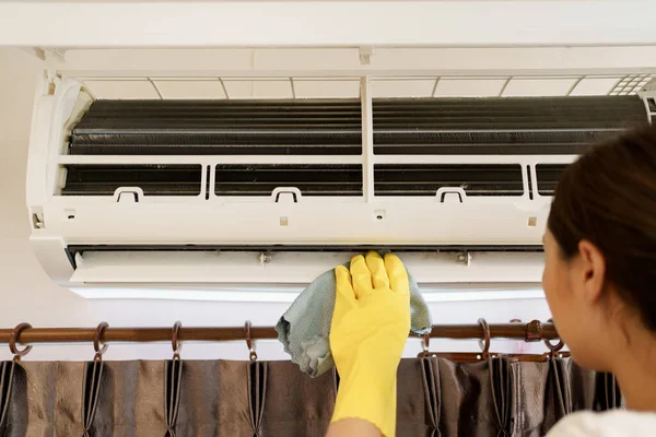 Asian woman cleaning a dirty and dusty air conditioning filter in her house. Housewife removing a dusty air conditioner filter.