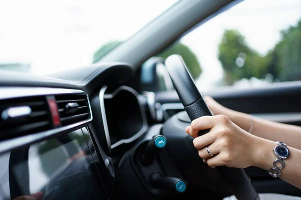 Happy Asian woman driving the electric vehicle - EV car smiling and showing her thumb up to the camera, happy and safety driving concept. Woman driving modern EV car and smiles to camera.