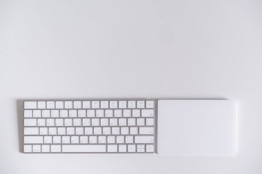 Modern wireless computer keyboard and touchpad on the white table, decorated in minimalist style with copyspace. Modern computer accessories and gadget.