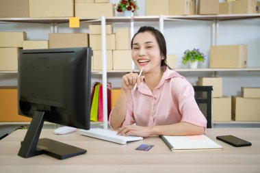 Çevrimiçi mal satıcısı müşterilere sevkiyat için iş yerinde paket hazırlıyor. Bir kadın uzun süre çalıştıktan sonra rahatlıyor ve kendini esnetiyor. ekommerce ticari ürün kavramı