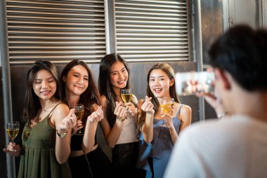 Group of cheerful young Asian people having a new year and Christmas celebrating together at the pub and restaurant, people enjoy cheering a beer and wine together.