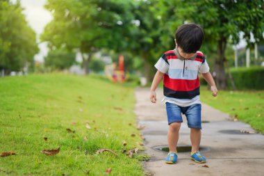 Oyun parkında oynayan ve rahatlayan Asyalı genç çocuk, masum çocuk portresi. Yakışıklı Asyalı çocuk kameraya bakıyor ve gülümsüyor. Fotoğraf için güzel bir doğası var..