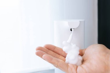 Woman washing her hands by using liquid soap foam from automatic water soap pumper bottle. Using touchless devices in an everyday lifestyles in healthcare people and avoid pandemic inflection.
