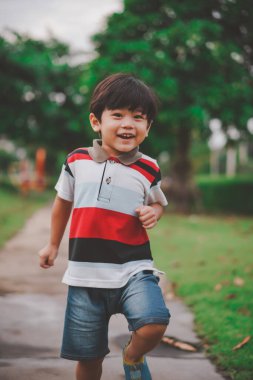 Oyun parkında oynayan ve rahatlayan Asyalı genç çocuk, masum çocuk portresi. Yakışıklı Asyalı çocuk kameraya bakıyor ve gülümsüyor. Fotoğraf için güzel bir doğası var..