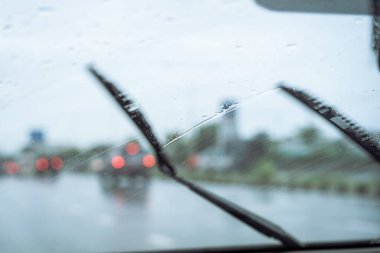 Driver activated windshield wipers to clean a raindrop on windshield away while driving on highway. Safe driving in raining season concept.