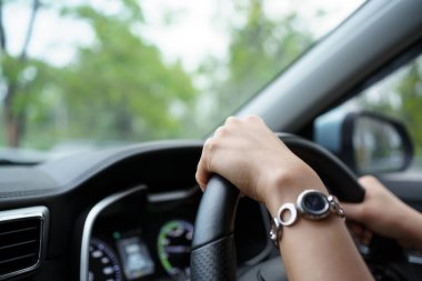 Yolda giderken direksiyonda sol elini kullanan tanınmayan kadın sürücü, yolda güzel bir gün ışığında modern elektrikli araba kullanan kadın. Güvenli sürüş kavramı.