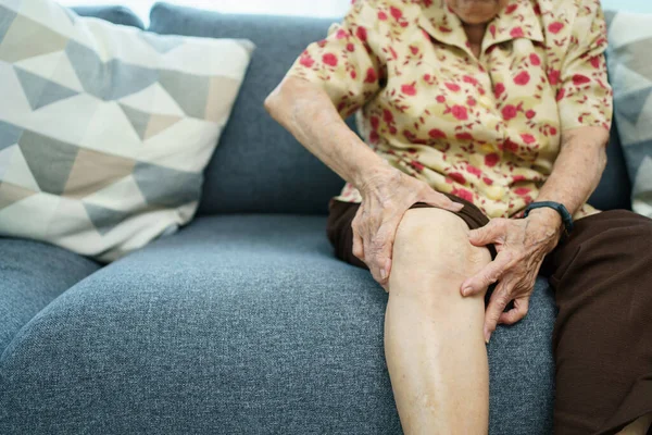 Asian elder woman having a critical health problem at knee and bone joint, woman touching or holding at knee. Elder woman getting hurt and injured at her leg.